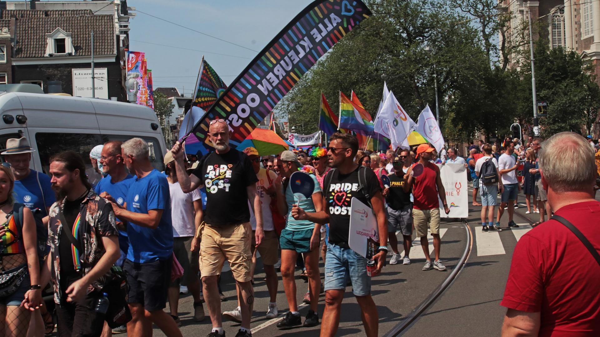 Marten tijdens Pride met de vlag van Alle Kleuren Oost