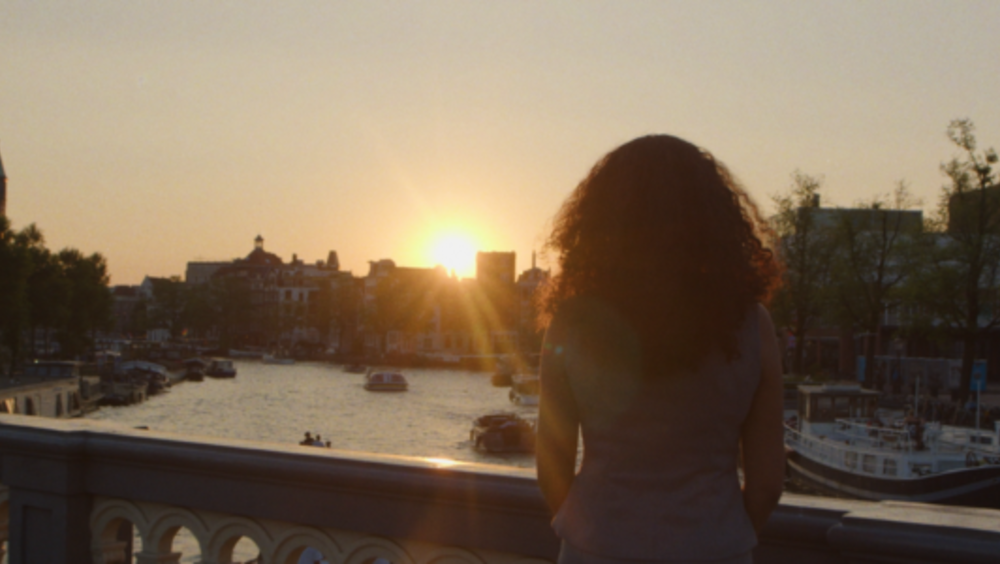 Imane staat op een brug een kijkt naar de zonsondergang