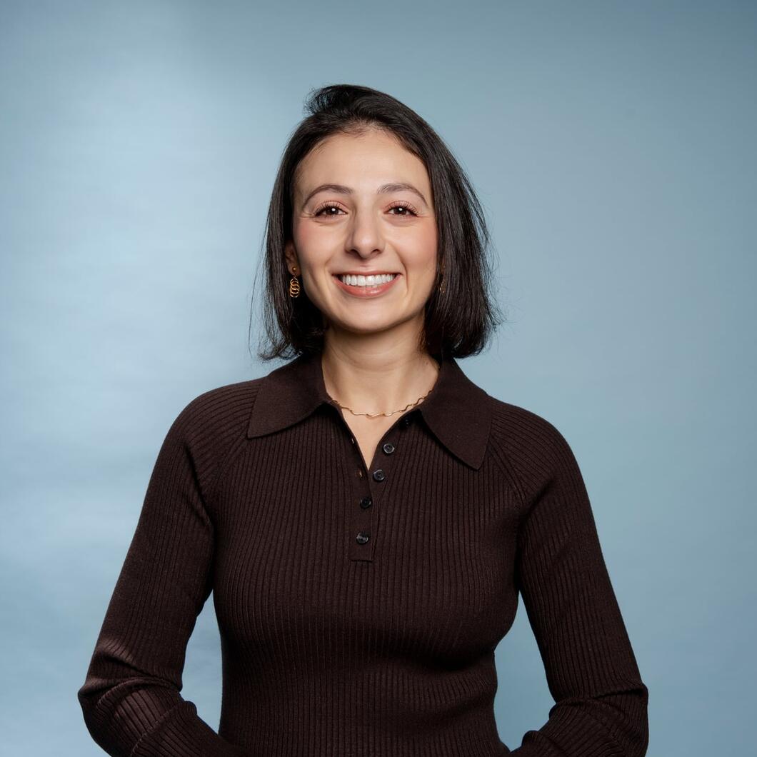 Pelin kijkt lachend in de camera met haar handen op haar rug