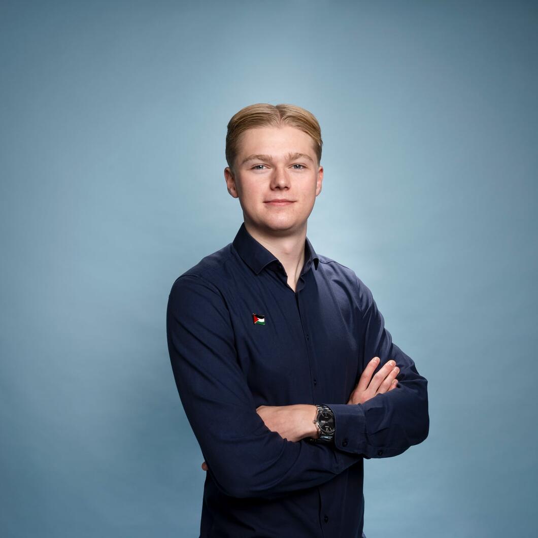 Pelle kijkt met zijn armen over elkaar glimlachend de camera in