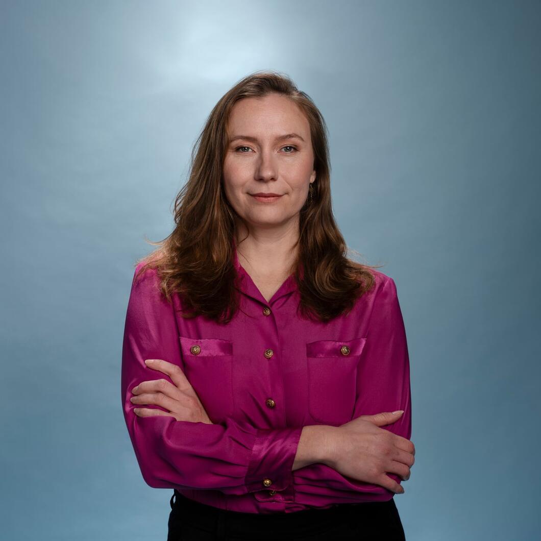 Zita Pels staat in een roze blouse met haar armen over elkaar