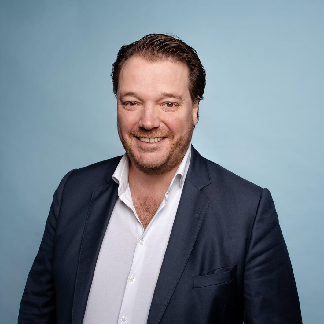 Carlo kijkt lachend de camera in