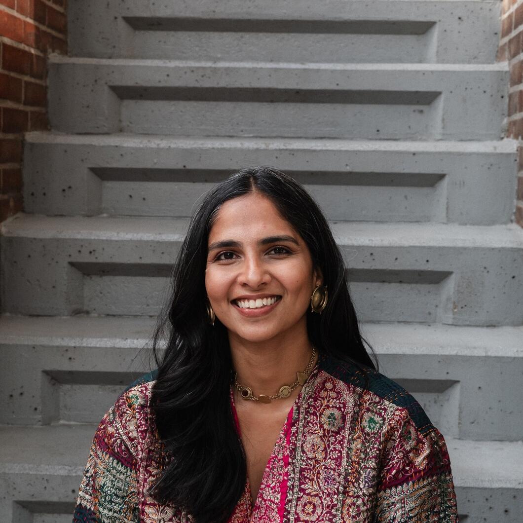 Rashi zit op een trap en kijkt lachend in de camera