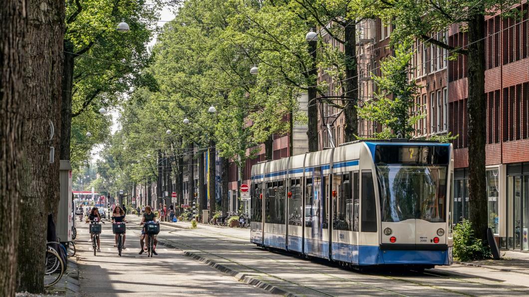 Tram in straat met bomen en fietsers