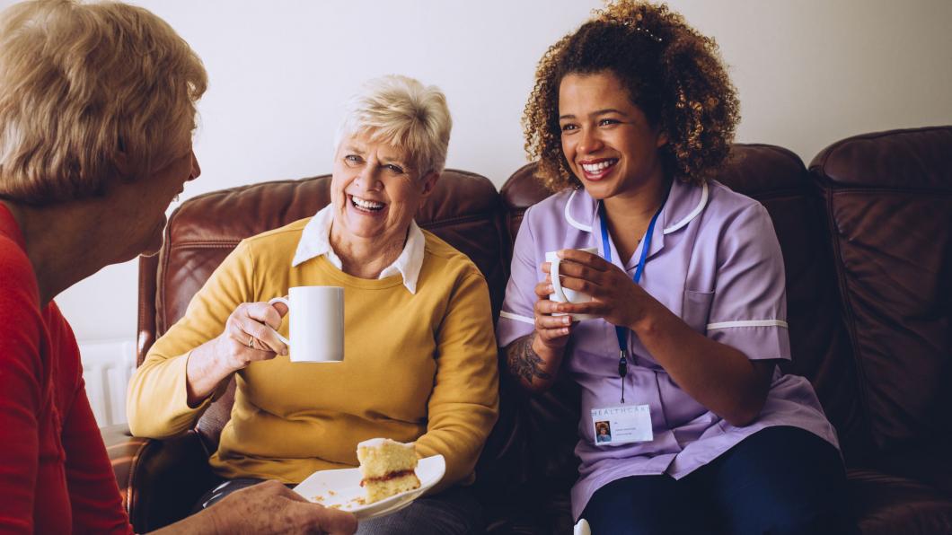 Drie vrouwen lachen met koffie en gebak