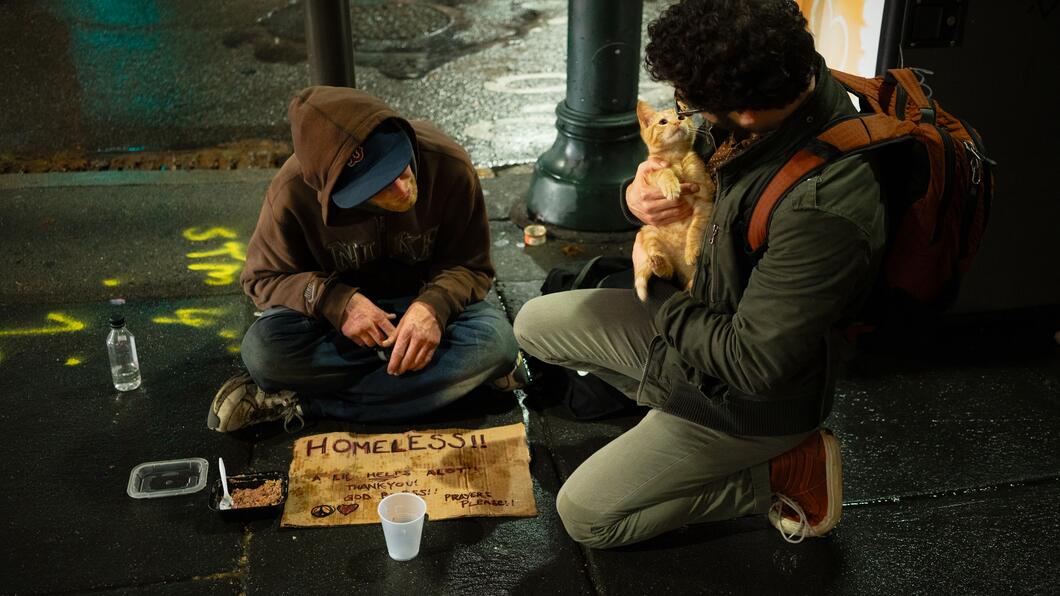 Zac Durant Unsplash: twee dakloze mannen zitten op straat, met een klein poesje