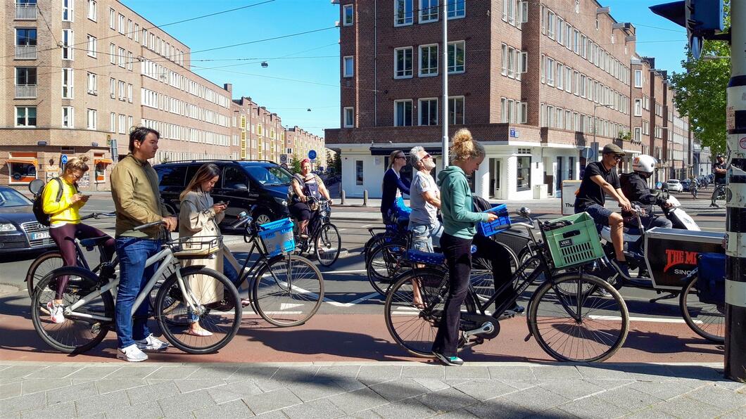 Fietsers wachten voor open brug; sommigen benutten die tijd om de mobiele telefoon te raadplegen  