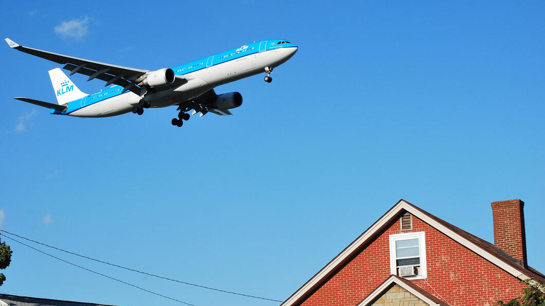 Vliegtuig van KLM vliegt over een huis met een schoorsteen