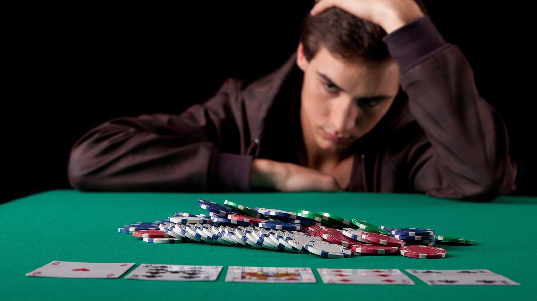 Foto van man achter een pokertafel die niet meer verder wil spelen omdat hij depressief is