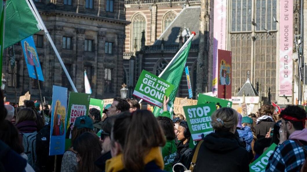 een volle Dam met vlaggen en protestborden