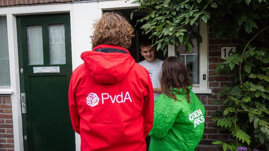 twee personen met een GroenLinks en PvdA jasje bellen aan