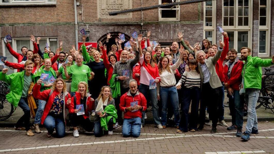 een groep in groene en rode jasjes staat juichend samen