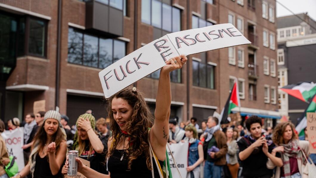 een demonstrant met een protestbord racisme/fascisme