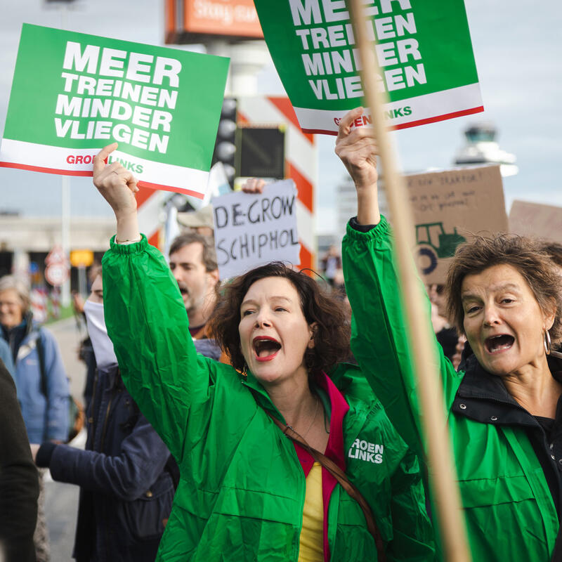 GroenLinks Politici bij een demonstratie met borden ' Minder vliegen, meer treinen'