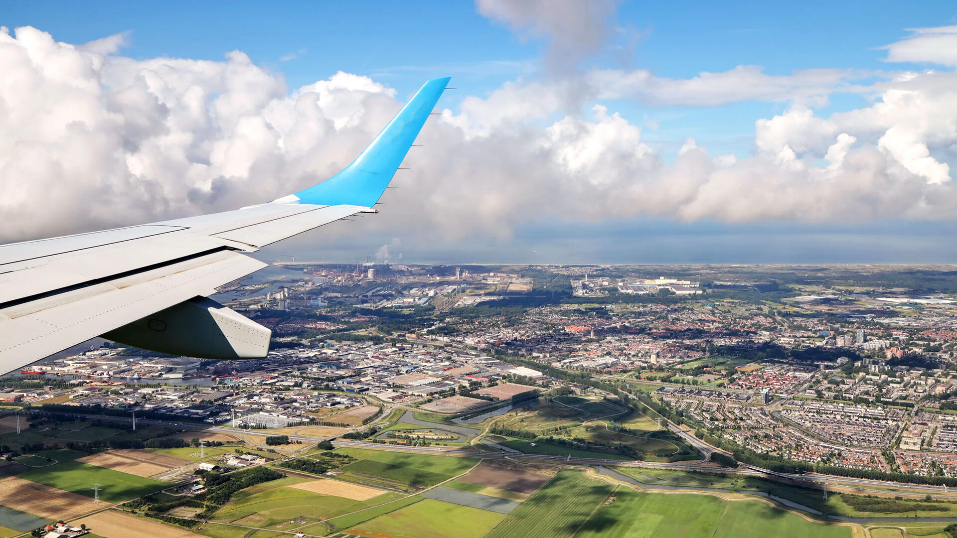 Een foto vanuit een vliegtuig met een landschap en de vleugel in beeld