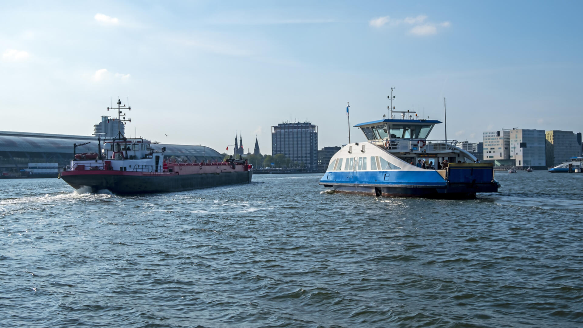 een groot schip en een pontje op het ij