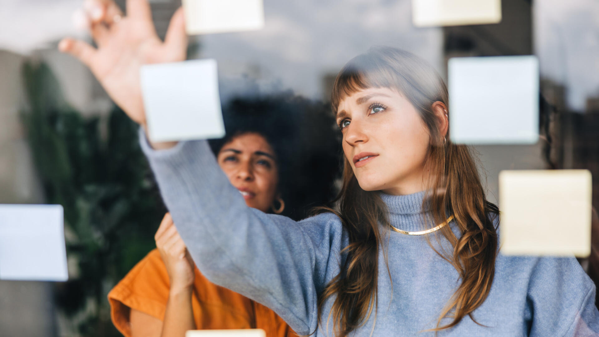twee vrouwen plakken post its op een raam