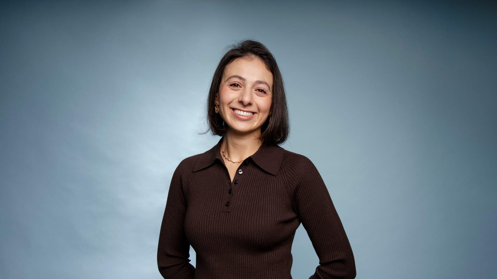 Pelin kijkt lachend in de camera met haar handen op haar rug