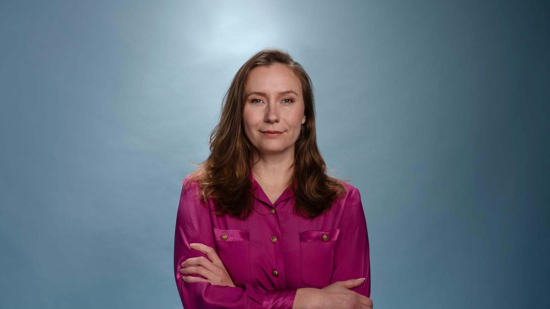 Zita Pels staat in een roze blouse met haar armen over elkaar