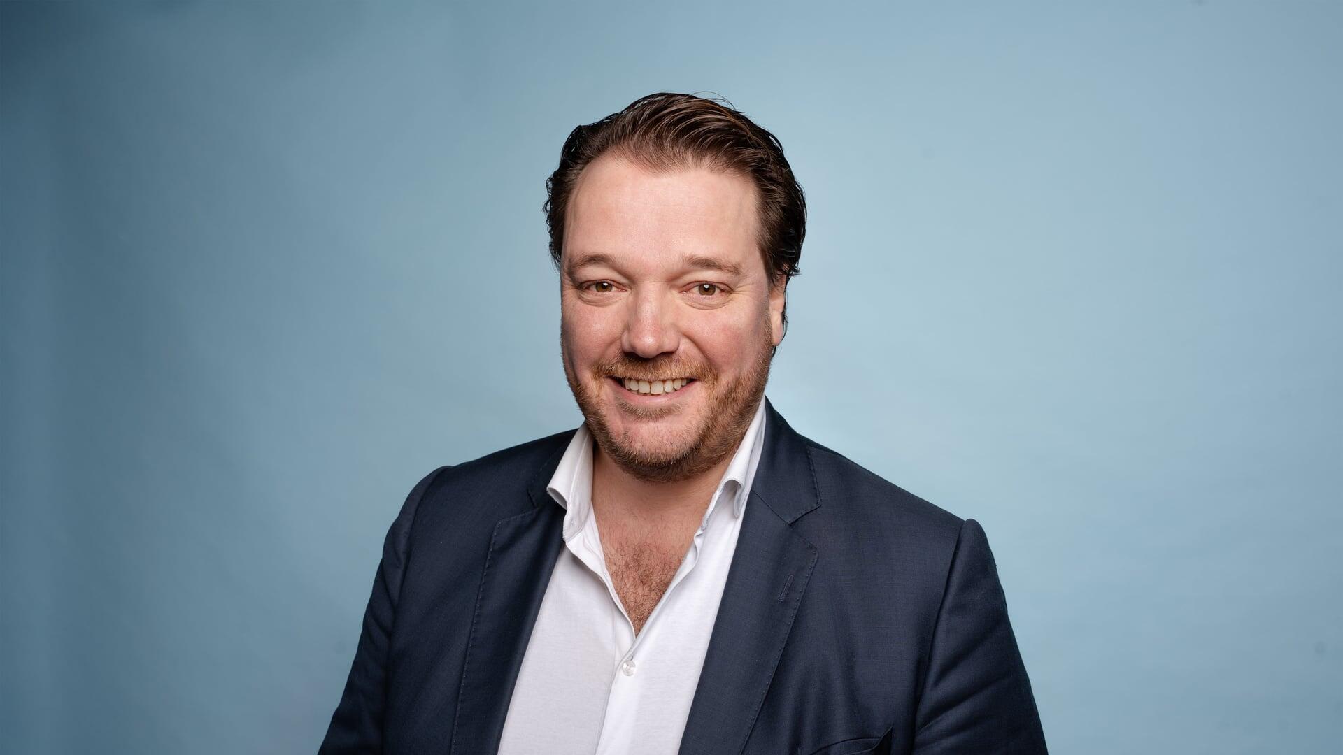 Carlo kijkt lachend de camera in