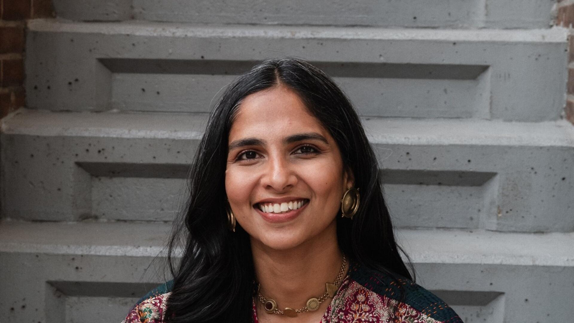 Rashi zit op een trap en kijkt lachend in de camera